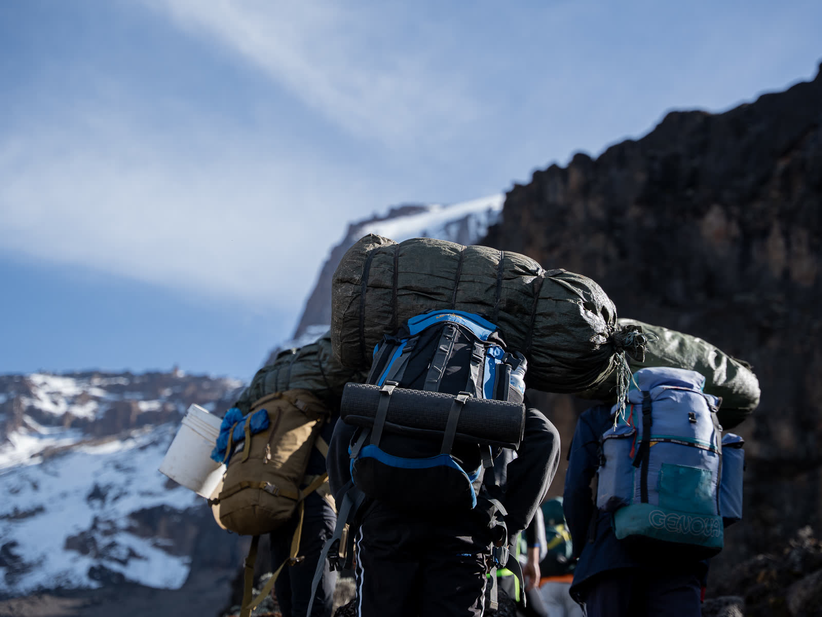 A mountain crew hiking beneath the Kilimanjaro skyline.